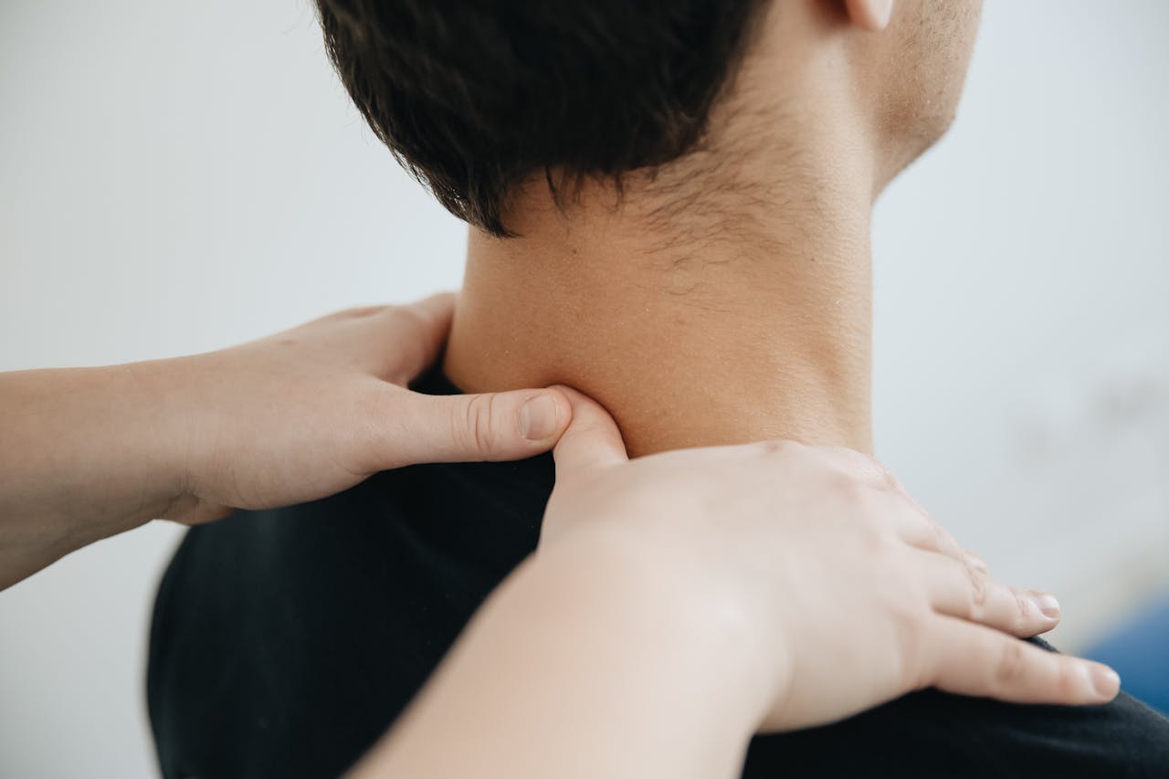 Close-up of a physiotherapist providing neck massage for pain relief in a clinic setting.